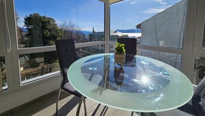 A glass table with chairs on a balcony with a view of mountains and buildings. - Andina View Bariloche (San Carlos de Bariloche)