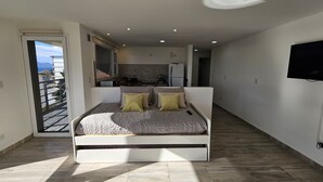 A modern bedroom with a bed, a TV, and a view of the kitchen. - Andina View Bariloche (San Carlos de Bariloche)