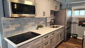 A modern kitchen with a stainless steel microwave, a built-in oven, a sink, and a refrigerator.