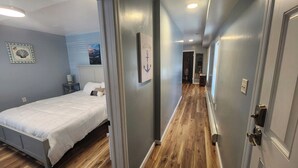 A hotel room with a bed, a nightstand, a wall-mounted TV, and a framed welcome sign.