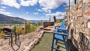 Un muro de piedra, asientos al aire libre y un jacuzzi con vistas a un lago.