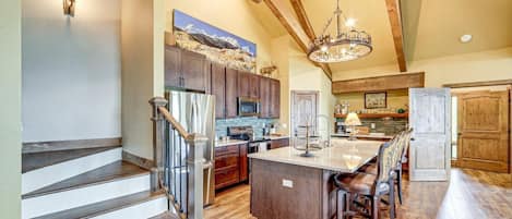 A spacious kitchen with wooden beams, a central island, and a dining area with chairs.