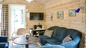 Una sala de estar acogedora con un sofá verde, una mesa de centro redonda y un televisor de pantalla plana montado en la pared.