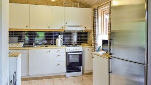 Una cocina compacta con armarios blancos, un refrigerador de acero inoxidable, una estufa a gas y un horno empotrado.