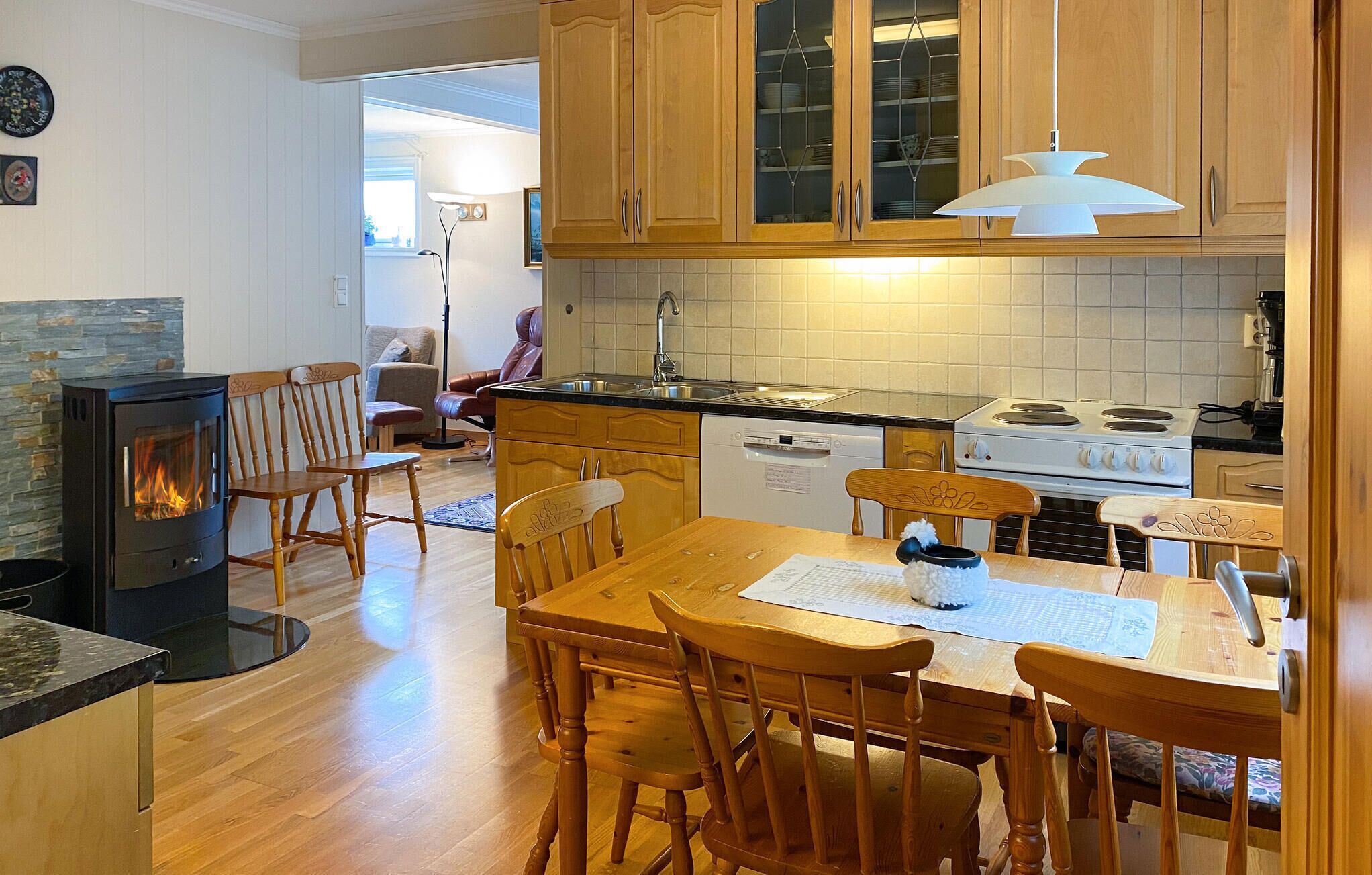 Una cocina acogedora con armarios de madera, una estufa y un comedor con mesa y sillas.