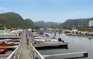 A marina with boats docked along a wooden pier, surrounded by green hills. - Cozy home in åheim with house a panoramic view (Åheim)