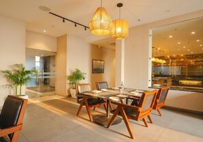 A modern dining area with a large table, chairs, and pendant lighting. - Rhythm Gurugram - Hotel & Suites (GURUGRAM)