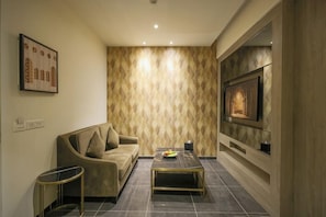 A living room with a sofa, coffee table, and a TV mounted on the wall.