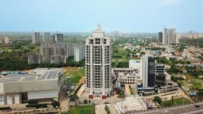 A high-rise building with a central courtyard, surrounded by other residential and commercial structures. - Rhythm Gurugram - Hotel & Suites (GURUGRAM)