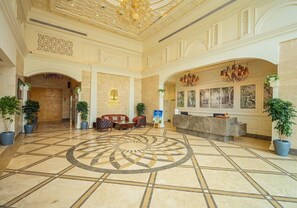 A hotel lobby with a central circular floor design, a reception desk, and seating area. - Rhythm Gurugram - Hotel & Suites (GURUGRAM)