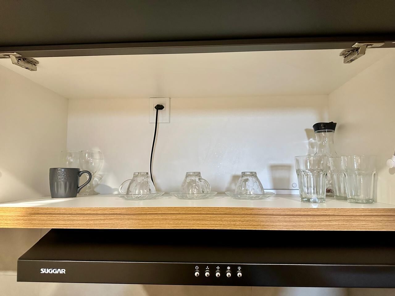 A kitchen shelf with various glassware and a coffee maker.