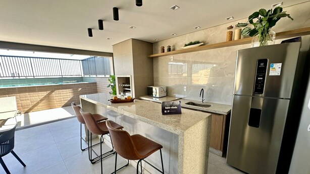 A modern kitchen with a stainless steel refrigerator, a built-in oven, and a bar area with stools. - Loft 506, 200 meters from Uberlândia Center Shopping (Saraiva Uberlândia)