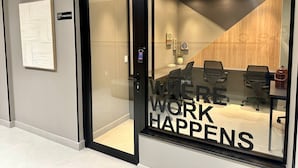 A modern office space with a glass door, a conference table, and office chairs. - Loft 506, 200 meters from Uberlândia Center Shopping (Saraiva Uberlândia)