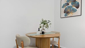 A round wooden table with a vase of flowers and a small framed picture.