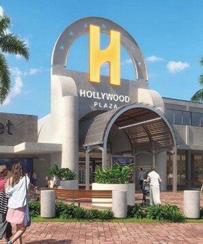 The Hollywood Plaza entrance with a prominent 'H' sign, a covered walkway, and surrounding greenery.