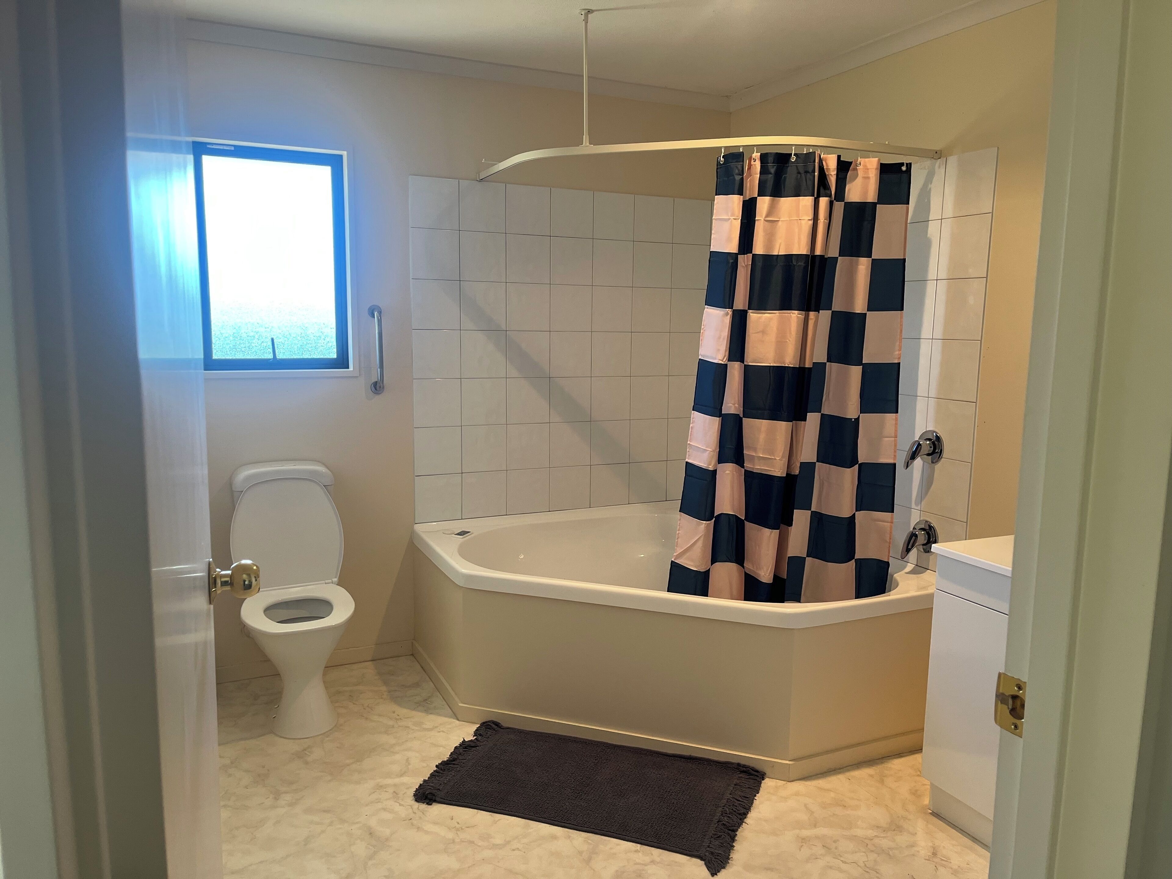 A bathroom with a toilet, bathtub, and a window.