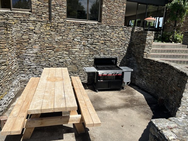 A stone wall, a wooden picnic table, and a portable grill.