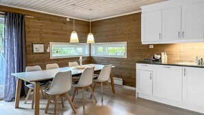 A modern kitchen with white cabinets, a dining area with a table and chairs, and two pendant lights.