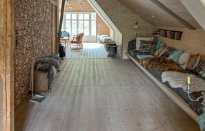 Une pièce confortable de style loft, avec un plancher en bois, un canapé agrémenté de plusieurs coussins, une petite table et une chaise.