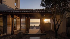 A traditional Japanese-style building with a view of the sea at sunset.