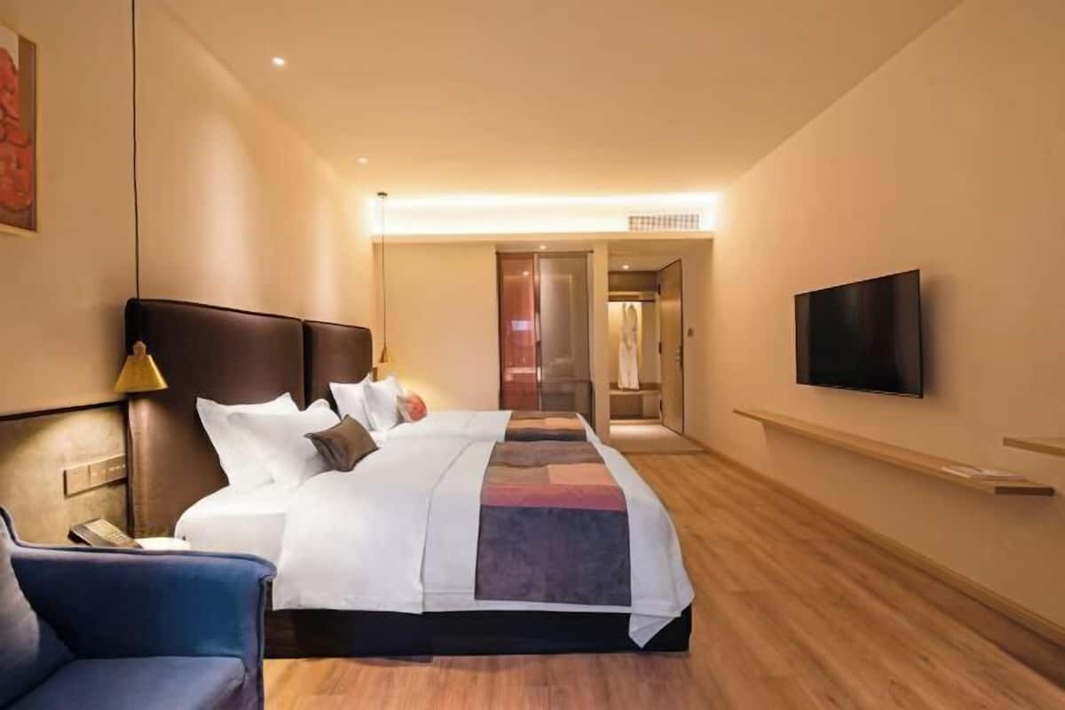 Een hotelkamer met een bed, een televisie, een bureau en een stoel.
