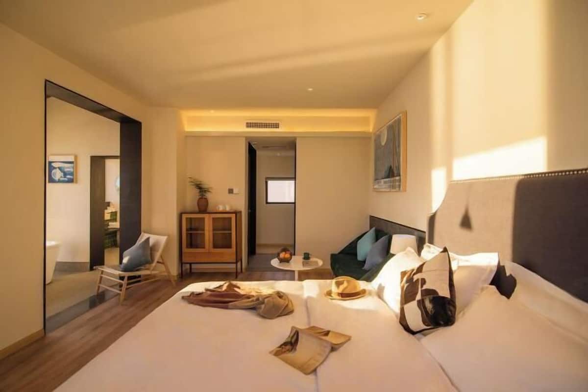 Een hotelkamer met een bed, een stoel, een klein tafeltje en een kast.