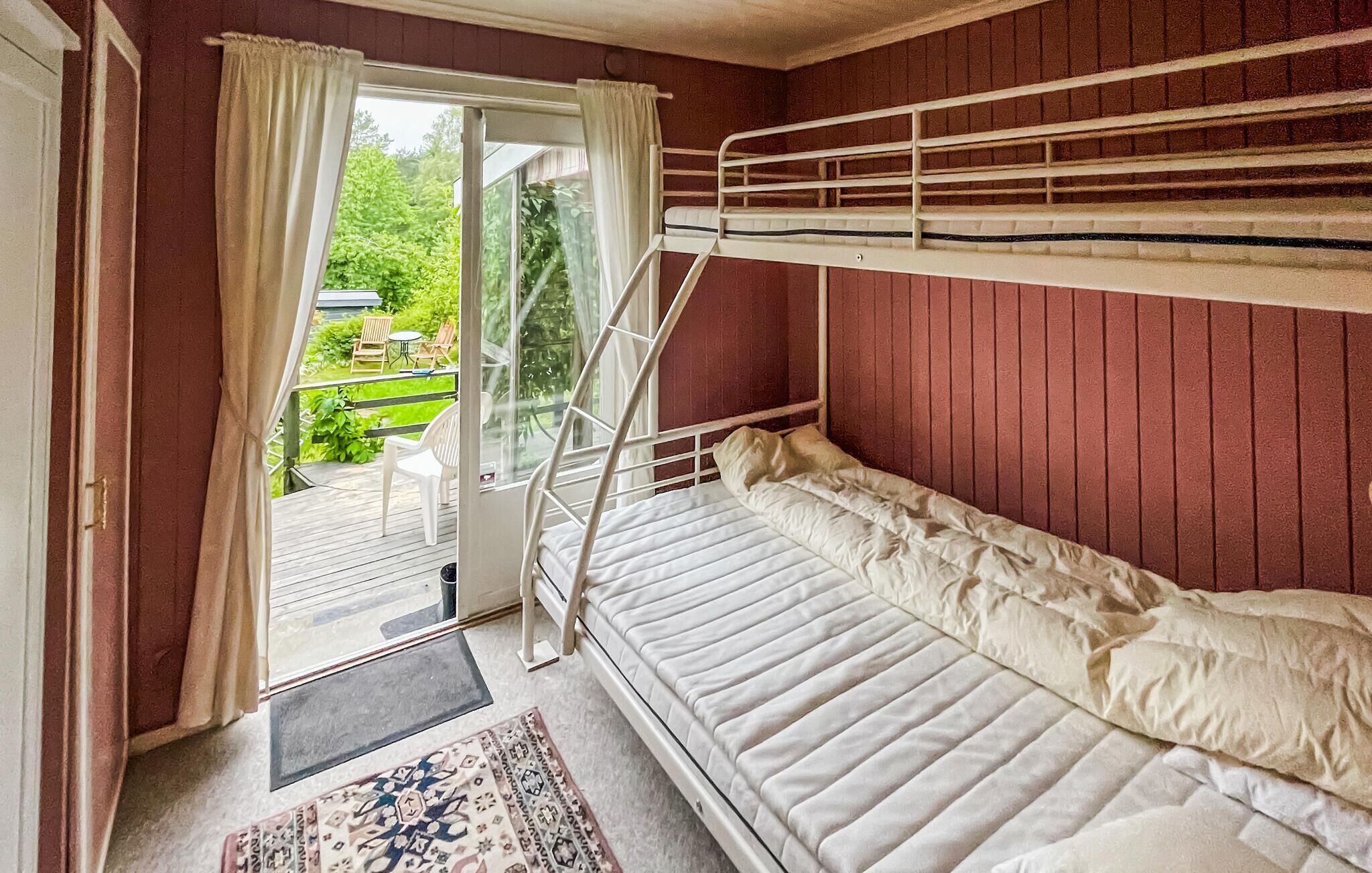 A bunk bed room with a sliding glass door leading to a balcony with outdoor furniture.