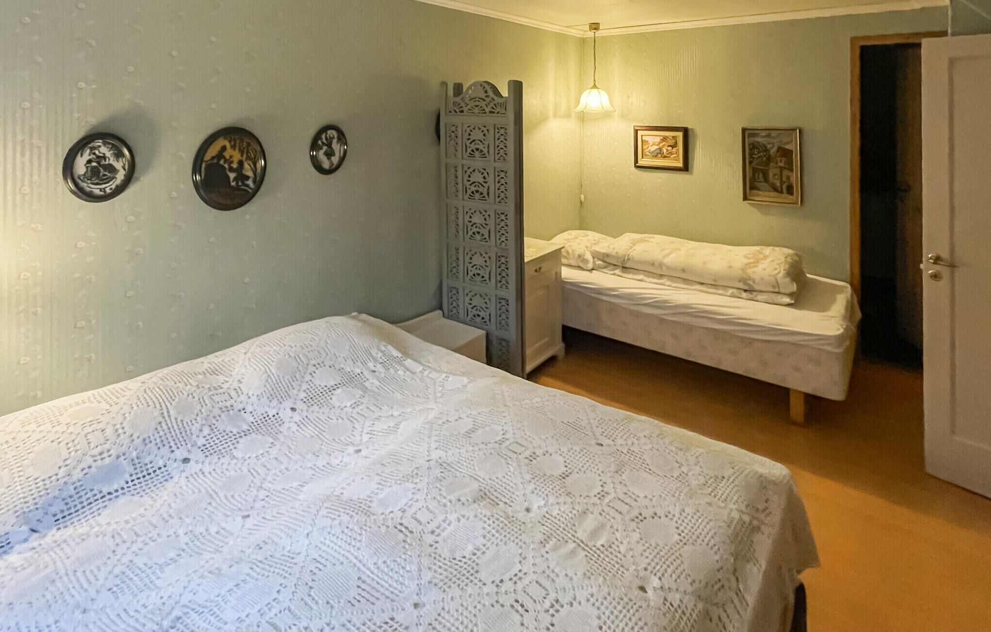 A bedroom with two beds, a wardrobe, and wall-mounted artwork.