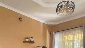 A living room with a flat-screen TV, two sofas, a coffee table, and a decorative plant. - 4Bedroom Family Home in Moshi (Moshi)