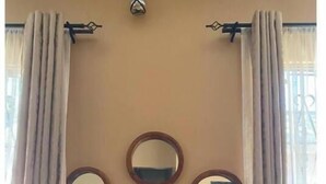 A room with a beige wall, three round mirrors, a vase with white flowers, a wooden console table, and two small black objects on the table. - 4Bedroom Family Home in Moshi (Moshi)