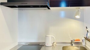 A modern kitchen with a built-in stove, a kettle, and a sink with a soap dispenser. - CRYSTAL&RESORT EXCLUSIVE (Fukuoka)