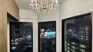 A modern room with a chandelier, large windows with city views, and a polished black floor. - CRYSTAL&RESORT EXCLUSIVE (Fukuoka)