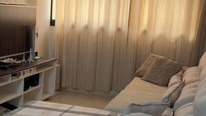 Una sala de estar moderna con un sofá, un televisor de pantalla plana y un mueble de madera.