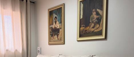 A living room with a sofa, a patterned throw, and two framed paintings on the wall.
