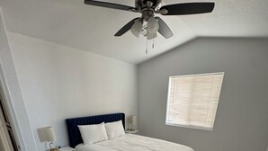 A bedroom with a bed, a nightstand, a chair, a ceiling fan, and a window with blinds. - Perfect for Families & Groups in Fortuna Foothills (Yuma)