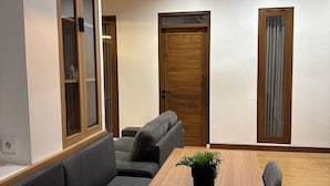 Un salon moderne avec une table à manger en bois, des canapés gris et un ventilateur de plafond.