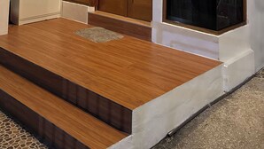 Une entrée moderne avec une porte en bois, une fenêtre en verre et un petit meuble blanc.