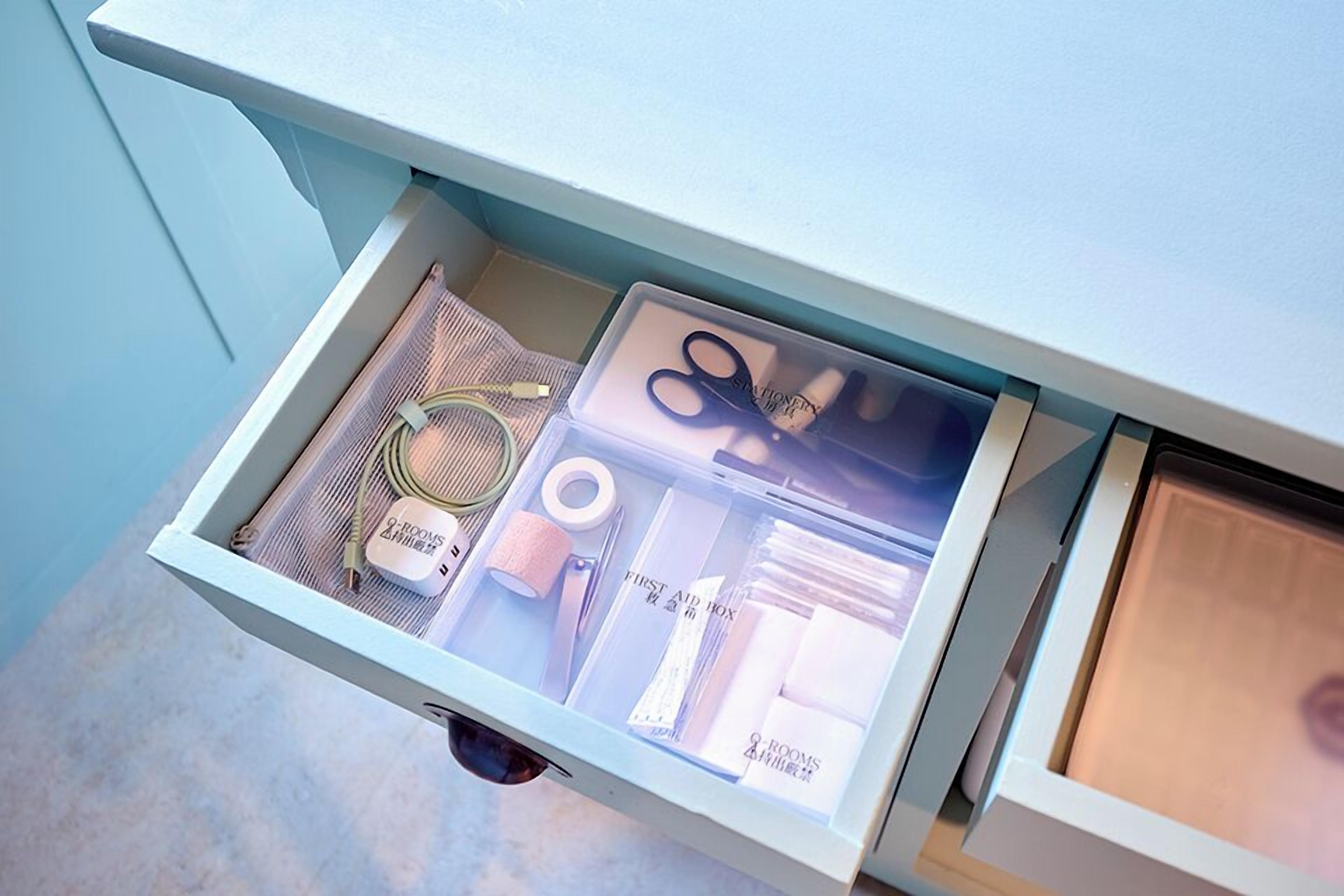 A drawer with neatly organized stationery items including scissors, tape, and a box labeled '2 rooms.'
