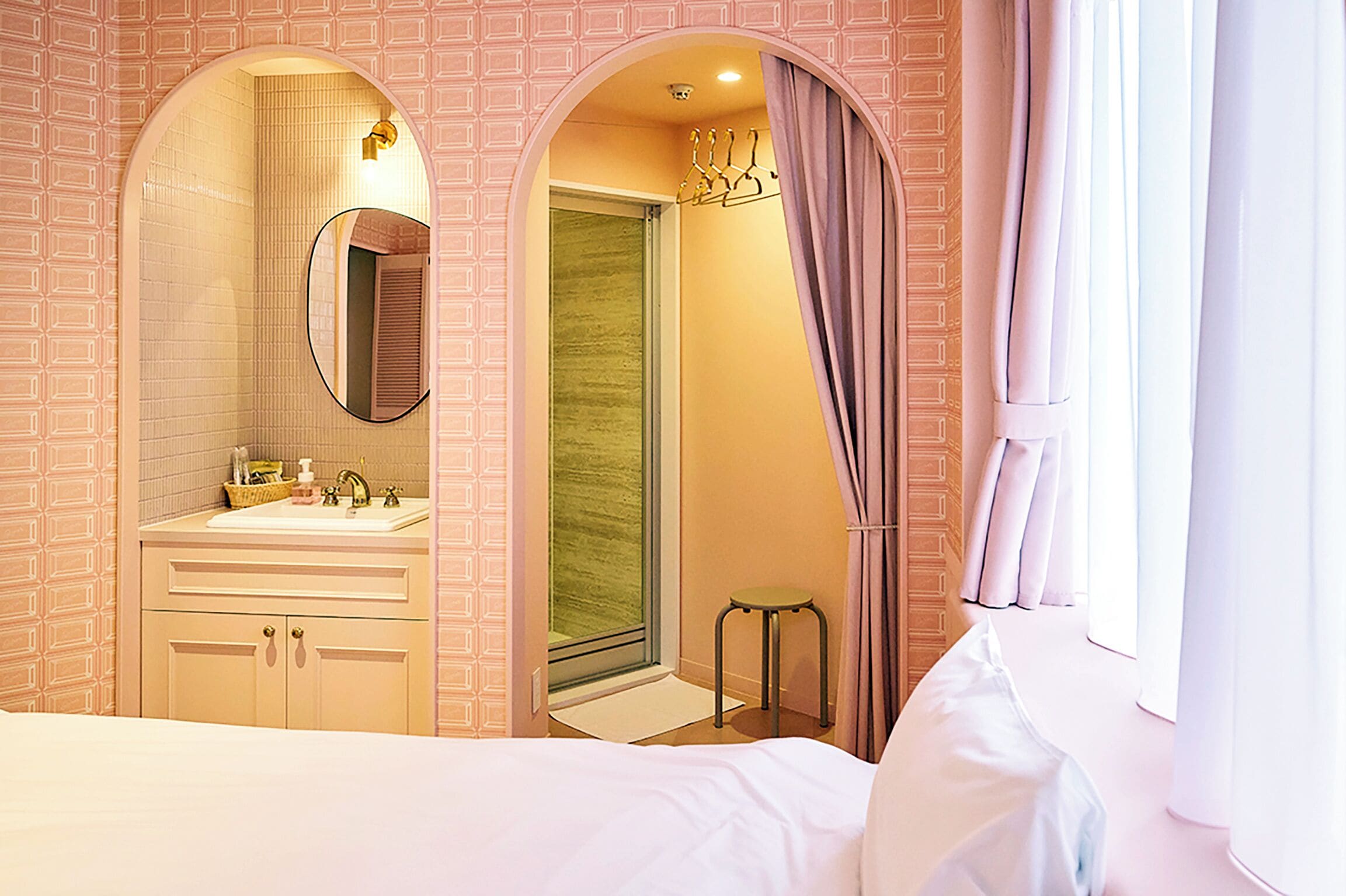 Una camera d'albergo con un letto grande, una toeletta con specchio, una doccia e una finestra con tende.