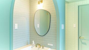Een badkamer met een witte wasbak, een ronde spiegel en een lamp erboven.