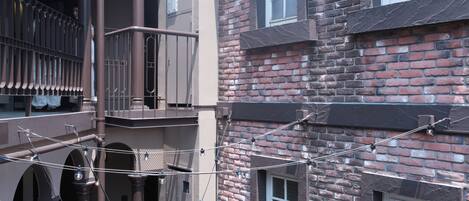 Un edificio de varios pisos con fachada de ladrillo, múltiples ventanas y un balcón con barandilla de metal.