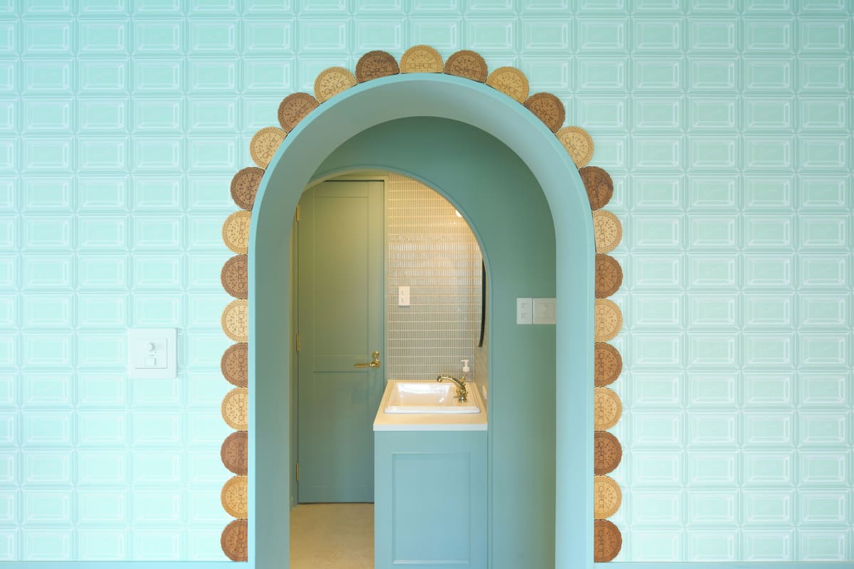 A bathroom with a light blue wall, a white sink, and a door with a gold handle.