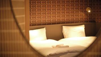 Una habitación de hotel con pared estampada, cama bien hecha y ventana circular.