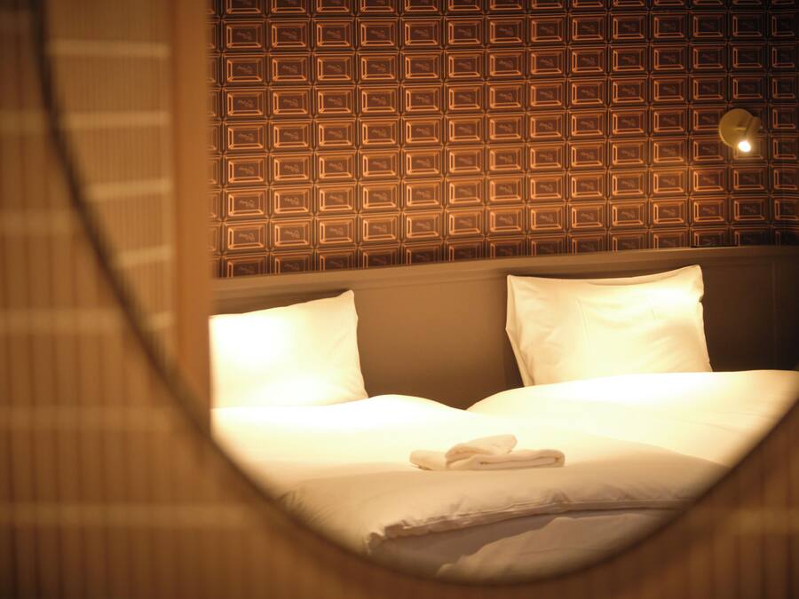 Una habitación de hotel con pared estampada, cama bien hecha y ventana circular.