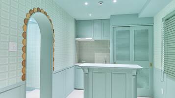 A kitchen with light blue cabinetry, a white countertop, and a decorative archway.