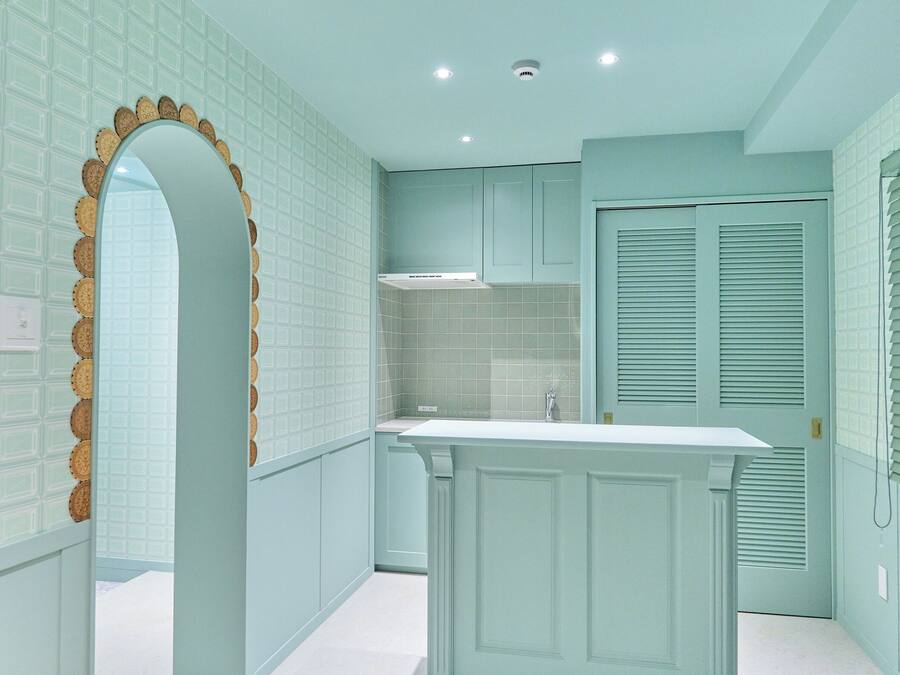 A kitchen with light blue cabinetry, a white countertop, and a decorative archway.