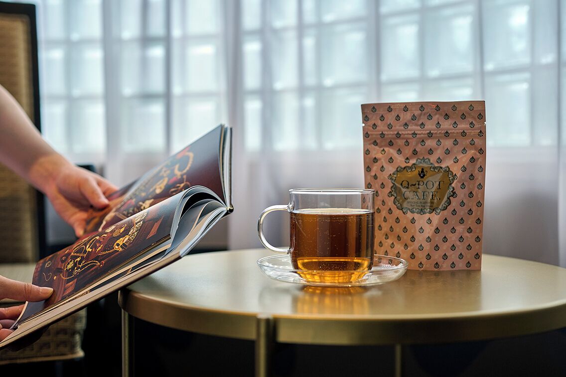 Ein Tisch mit einer Tasse Tee, einem Buch und einer gemusterten Tasche.
