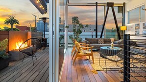 Une terrasse moderne sur le toit, dotée d’un foyer, de sièges et offrant une vue sur le coucher du soleil.