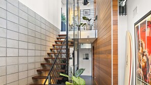 Un intérieur moderne avec un escalier en bois, une plante en pot et une affiche de planche de surf.