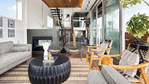 Un salon moderne doté d’une cheminée, d’un espace salon et d’un escalier menant à un niveau supérieur.